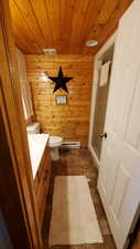 Bathroom featuring vanity, wood ceiling, a shower stall, wood walls, and dark tile patterned floors
