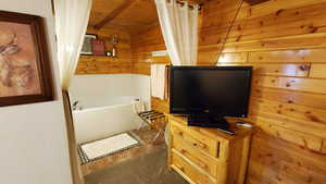 Bathroom featuring wood walls, a garden tub, and wood ceiling