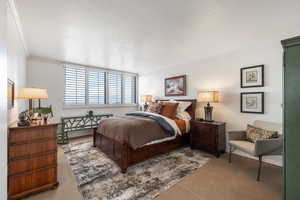 Carpeted bedroom featuring crown molding and baseboards