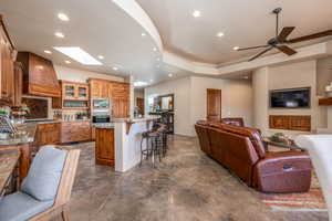 Kitchen featuring glass insert cabinets, a breakfast bar, recessed lighting, open floor plan, and brown cabinets