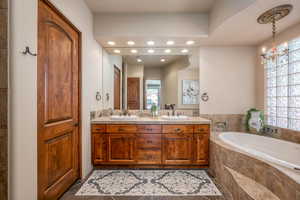 Bathroom with double vanity, a garden tub, recessed lighting, and a chandelier