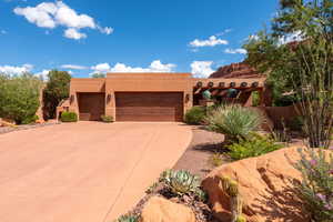Pueblo-style house featuring a garage, stucco siding, and driveway