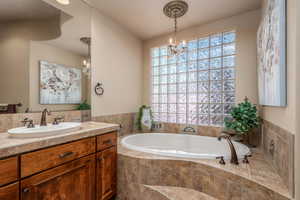 Full bathroom with a garden tub, vanity, and a chandelier