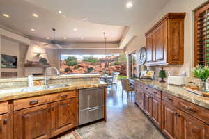 Kitchen with brown cabinets, ceiling fan, dishwasher, recessed lighting, and pendant lighting