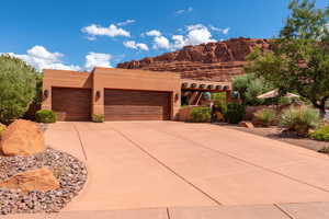 Pueblo-style home featuring driveway, stucco siding, and a garage