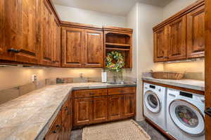 Laundry area featuring cabinet space, washer and clothes dryer, and dark tile patterned floors