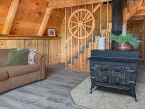 Living area featuring a wood stove, wood finished floors, wooden walls, and wood ceiling