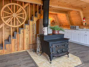 Detailed view of a wood stove, a wood ceiling with exposed beams, wood finished floors, wood walls, and stainless steel microwave