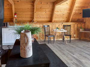 Living area with wood finished floors, a wooden ceiling with exposed beams, and wood walls