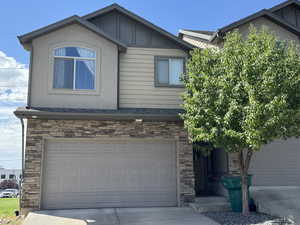 View of front of home with stone siding, roof with shingles, and concrete driveway