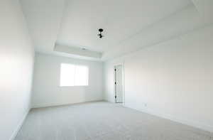 Unfurnished room featuring a tray ceiling and carpet