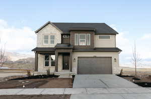 View of front facade featuring stone siding, a garage, driveway, stucco siding, and a shingled roof