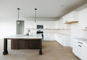 Kitchen featuring appliances with stainless steel finishes, white cabinets, decorative light fixtures, and decorative backsplash
