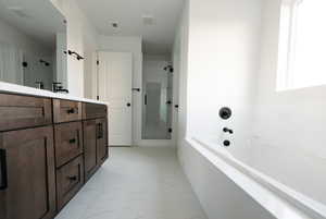 Full bath featuring double vanity, light marble finish flooring, a garden tub, and a shower stall
