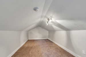 Bonus room featuring light colored carpet and vaulted ceiling