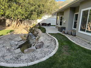 Fenced backyard featuring a patio and a garden pond