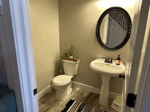 Half bath with baseboards and wood finished floors