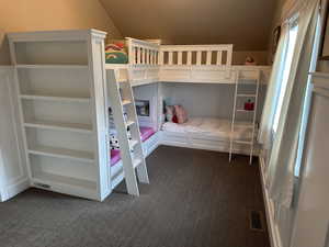 Bedroom featuring dark colored carpet and lofted ceiling