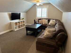 Carpeted living room with ceiling fan and vaulted ceiling