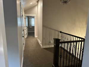 Hallway featuring dark carpet, vaulted ceiling, and recessed lighting