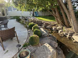 Fenced backyard featuring a playground and a patio area