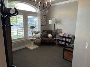 Living area with carpet floors, crown molding, and a chandelier