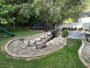 View of yard featuring a trampoline, a playground, and a patio
