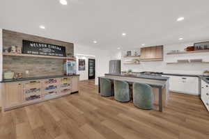 Kitchen with open shelves, a center island, recessed lighting, decorative backsplash, and light wood finished floors