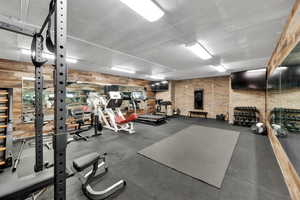 500 sq ft custom workout area featuring brick and reclaimed barn wood walls and mirrors