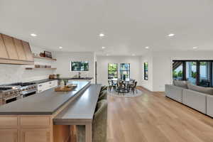 Kitchen with custom range hood, dark countertops, recessed lighting, light wood-style floors, and double oven range