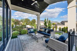 Wooden deck featuring outdoor lounge area, ceiling fan, a patio, and a residential view