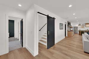 Hall with recessed lighting, light wood-type flooring, and a barn door