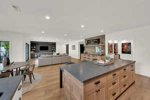 Kitchen featuring dark countertops, light wood-style flooring, recessed lighting, a kitchen island, and light brown cabinets