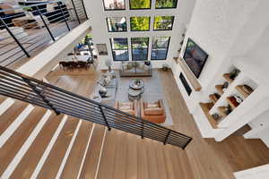 Sunken living room featuring wood finished floors, a glass covered fireplace, and a high ceiling