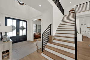 Foyer with stairs, recessed lighting, light wood-style floors, and french doors