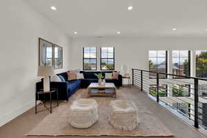 Loft area with recessed lighting and light carpet