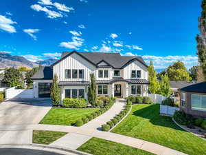 Modern farmhouse featuring board and batten siding, concrete driveway, a standing seam roof, a metal roof, and a shingled roof