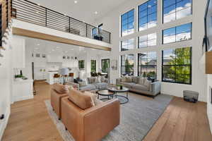 Living area featuring light wood finished floors, recessed lighting, a towering ceiling, and a fireplace