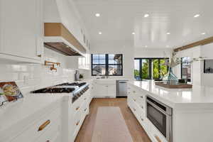 Kitchen with white cabinets, light stone counters, recessed lighting, light wood-type flooring, and stainless steel appliances