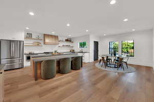 Kitchen featuring dark countertops, open shelves, freestanding refrigerator, recessed lighting, and a center island