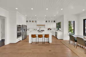 Kitchen with white cabinets, recessed lighting, a breakfast bar area, a center island, and appliances with stainless steel finishes