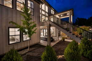 Back of house at twilight with stairs, a patio area, and a balcony
