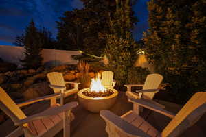Patio at night with a fenced backyard and an outdoor fire pit