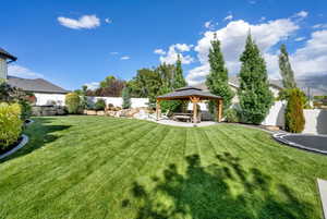 Fenced backyard with a patio area, a gazebo, and a trampoline