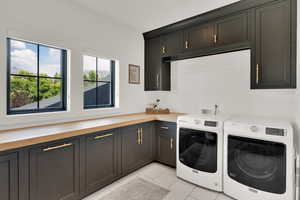 Laundry room with cabinet space, washing machine and clothes dryer, and light tile patterned floors