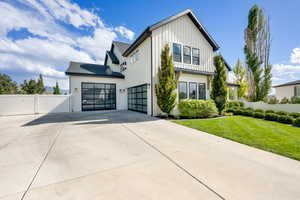 Modern farmhouse with a gate, concrete driveway, and board and batten siding