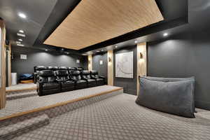 Carpeted cinema room featuring a tray ceiling and recessed lighting