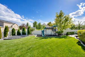 Fenced backyard with a playground and a trampoline