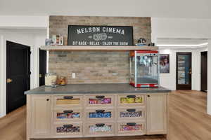 Bar featuring dark countertops, light wood-style floors, light brown cabinets, and open shelves