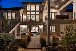Back of house at night with a patio area, an outdoor living space, ceiling fan, and stairway